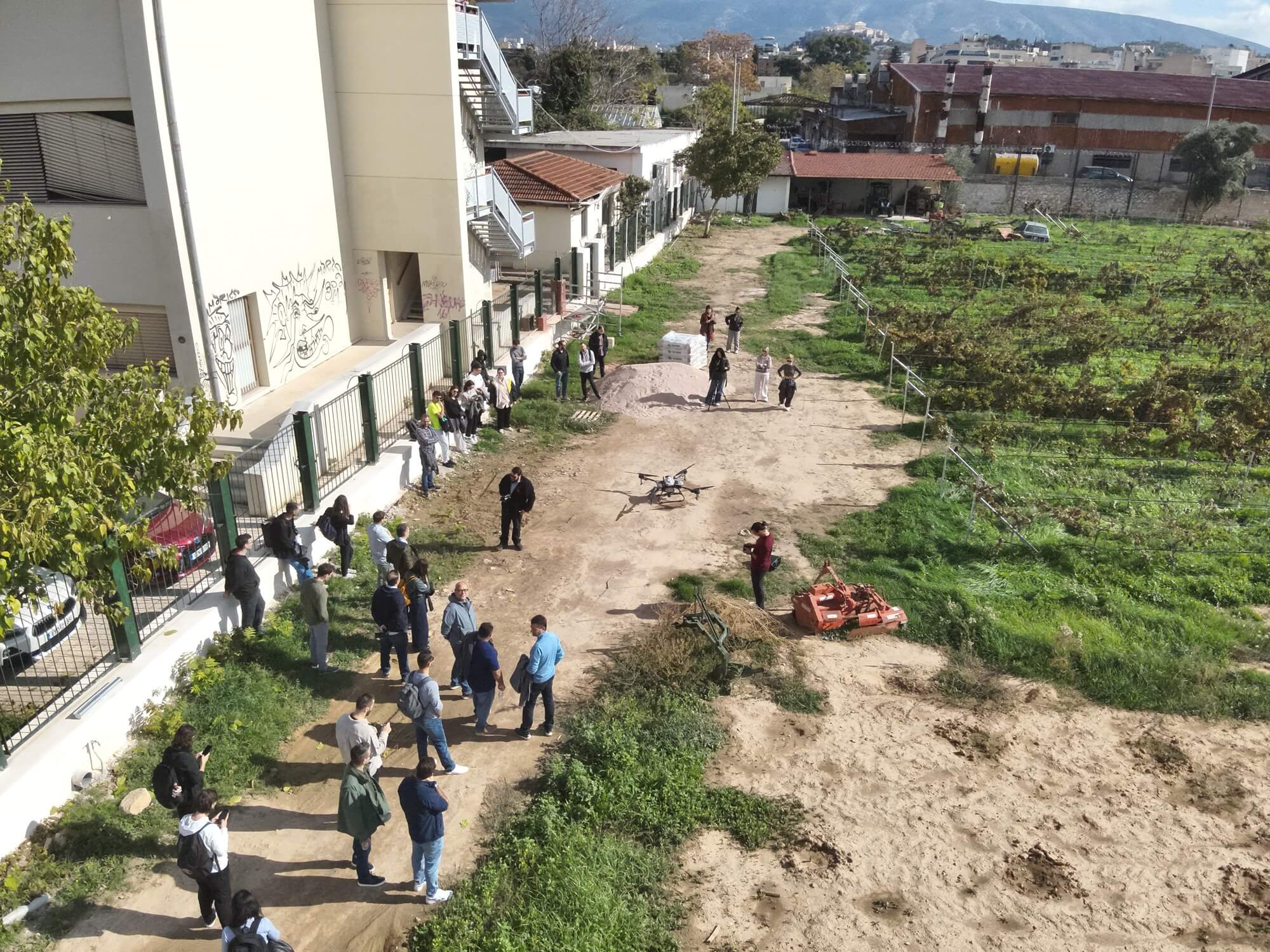 Aerial view of attendees watching the drone hover near the vineyard