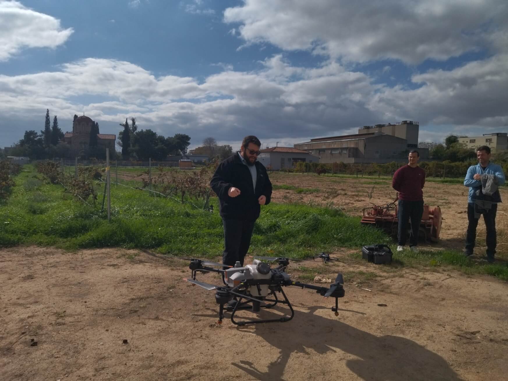 Spraying drone on the ground before flight, with the team looking on
